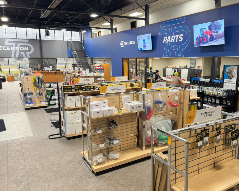 Tracey Road Equipment showroom with parts and reception desks, assorted truck and construction equipment accessories on display, and customers at service area.