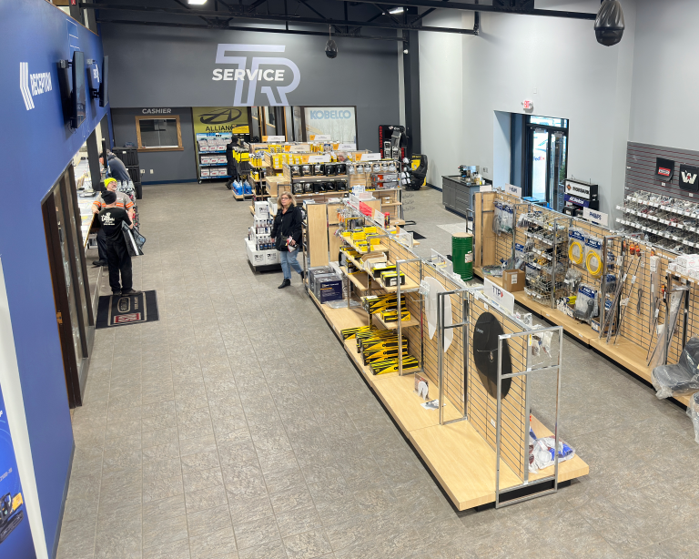 Interior view of Tracey Road Equipment's Syracuse showroom featuring the service counter, displays of heavy equipment parts and accessories, and customers browsing.