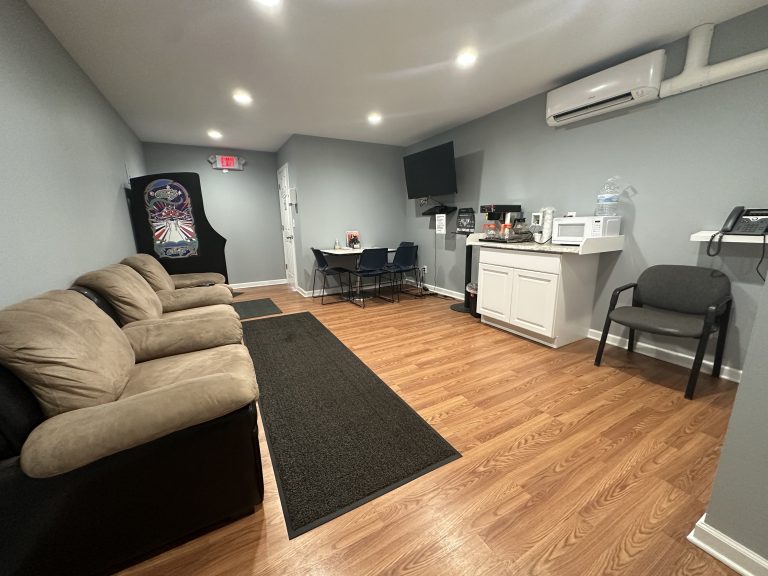 Albany branch waiting room with comfortable seating, a coffee station, and a dartboard arcade game.